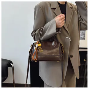 Detail view of a vintage dark brown leather boston bag with unique knot charm and strap