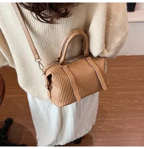 Detail of light brown pleated leather bucket bag with top handles and adjustable strap