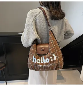 Detailed view of brown plaid tote bag with white 'hello' embroidery and leather strap