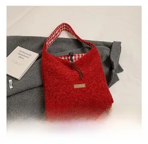 Detailed view of red faux shearling tote with plaid lining and leather brand label