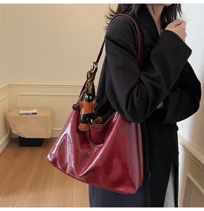 Detail of burgundy glossy leather tote bag with a cute cat charm for office outfits