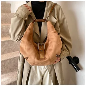 Macro shot of brown suede hobo bag with vintage metal buckle and decorative rivets