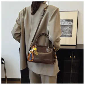 Detailed view of a vintage dark brown Boston bag with golden abacus charm and orange cord