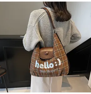 Detail of checkered tote bag with leather flap and embroidered hello lettering