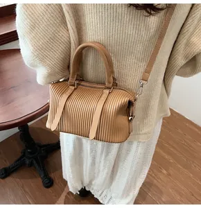 Detail of vintage coffee pleated boston bag with adjustable strap on a female model