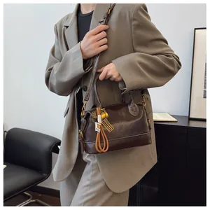 Detail of vintage brown leather Boston bag featuring white stitching and gold abacus charm