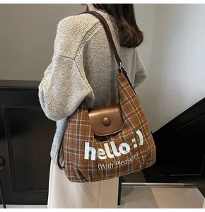 Detail shot of brown plaid tote bag with 'hello' embroidery and vegan leather accents