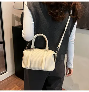 Detailed view of cream pleated bucket bag with gold hardware worn by a model
