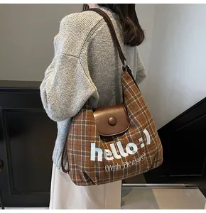 Detailed view of large brown plaid tote bag with leather strap and Hello embroidery