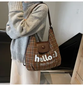 Detailed shot of brown checkered tote bag with flap and embroidered hello lettering