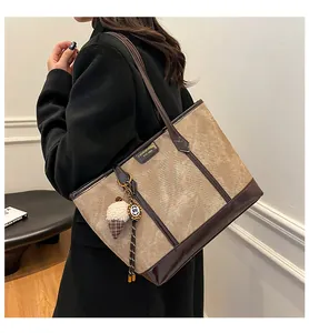 Détail du grand sac cabas en toile beige vintage avec bandoulière en cuir marron et logo