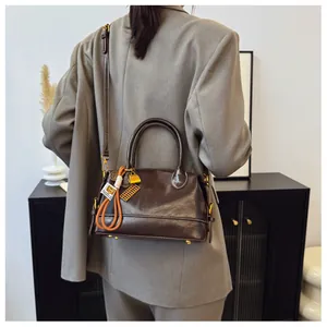 Detail of dark brown leather vintage doctor bag with gold charms and shoulder strap