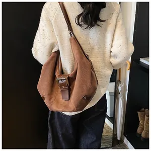 Detailed view of a brown suede hobo bag with vintage metal buckle on a model