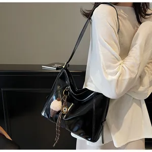 Detail of glossy black tote bag with plush ice cream pendant and a long shoulder strap