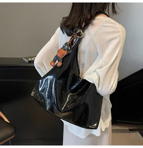 Detail of black glossy leather tote bag with a cute cat pendant and large capacity