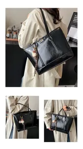Détail du grand sac cabas noir brillant avec fermoir doré et pendentif crème glacée