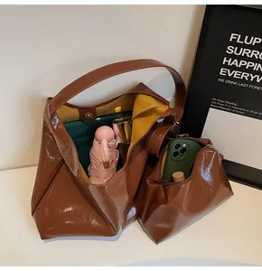 Detail of brown glossy tote bag with yellow lining showing spacious interior and pouch