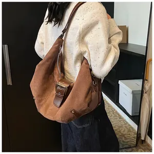 Detail of caramel brown suede hobo bag with dark leather strap and silver zipper