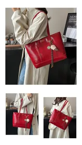 Vue détaillée d'un grand sac cabas rouge brillant avec pendentif en peluche chic