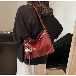 Close-up of deep red glossy leather tote bag with stylish round badge detail