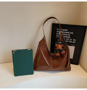 Detailed view of chocolate brown glossy leather hobo bag with a cute bear charm