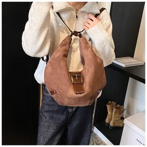 Close-up of a brown matte hobo bag featuring a vintage metal buckle and zipper closure