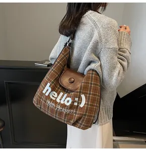 Close-up of retro plaid shoulder bag with brown leather flap and 'hello' embroidery