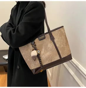 Détail du sac cabas en tissu kaki avec finitions en cuir marron et pendentif