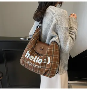 Brown checkered shoulder bag with white embroidery detail shown on a model's back