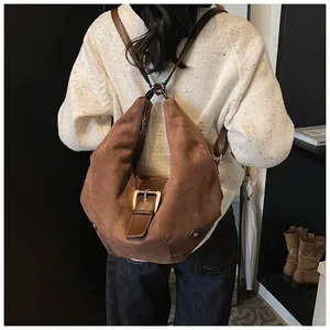 Close-up of retro dark brown suede shoulder bag featuring a large metal buckle on the back
