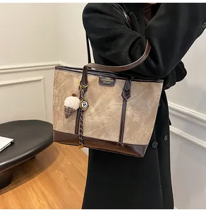 Détail du sac cabas en toile kaki avec garniture en cuir verni marron et breloque glace