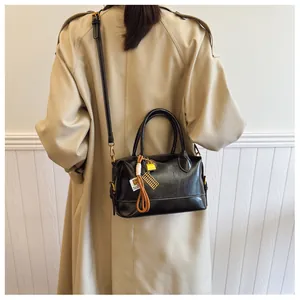 Close-up of black leather Boston bag with gold hardware and abacus charm detail