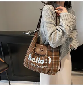 Detail of vintage brown plaid tote featuring hello embroidery and leather flap closure