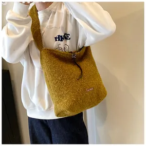 Detail of mustard yellow plush tote bag showing grainy texture and small leather tag