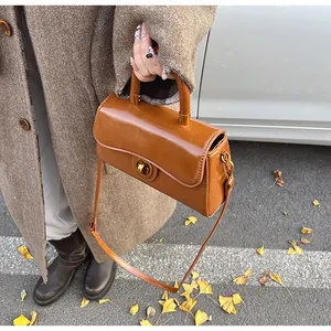 Detailed view of caramel leather handbag with gold twist lock for autumn outfits