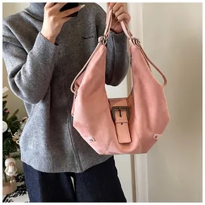 Close-up of pink suede hobo bag featuring a large metal buckle and dual shoulder straps