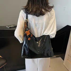 Black crinkled patent leather tote bag with silk scarf and charm shown from back
