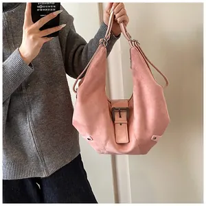 Pink suede hobo bag with vintage metal buckle and adjustable strap shown in a mirror selfie