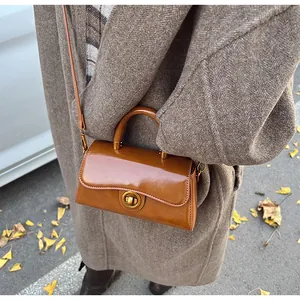 Detail of vintage brown leather handbag with a round metal clasp in an autumn street setting