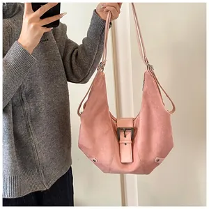 Detail of pink hobo bag featuring matte suede texture and vintage metal buckle strap