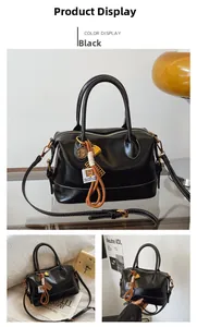 Detail of black leather Boston bag with white contrast stitching and colorful pendants