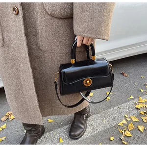 Detail of glossy patent leather handbag with gold clasp in an autumn street setting