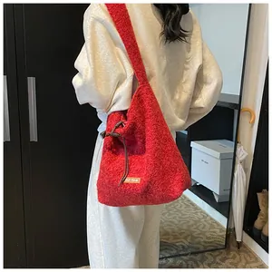 Detail of red plush tote bag with drawstring and fabric label on casual outfit