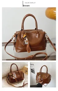 Detailed view of brown retro Boston bag with metallic abacus charm and leather texture