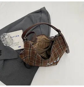 Macro view of plaid tote bag featuring brown wool texture and striped interior lining