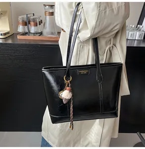 Détail d'un sac cabas en similicuir noir brillant avec un charmant pompon de glace