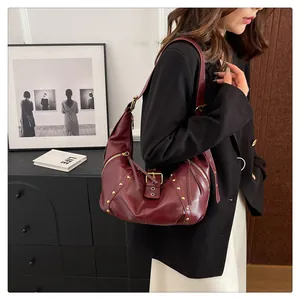 Detailaufnahme der burgunderroten Hobo-Tasche mit Goldnieten und verstellbarem Riemen