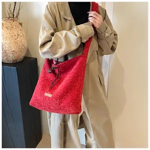 Detail of red fuzzy tote bag with 'our fave' label and drawstring closure