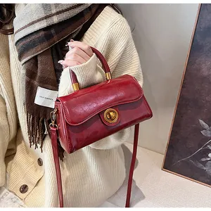 Close-up of vintage dark red glossy leather handbag with golden round swivel lock