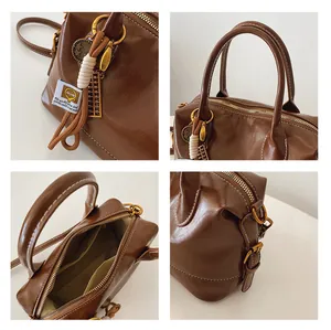 Detail of vintage brown leather Boston bag with white stitching and golden hardware